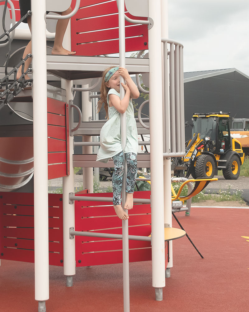 Ein kleines Kind Rutschen auf einem Spielplatz eine Feuerwehrstange hinunter, sie befindet sich in der Mitte des Bildes.